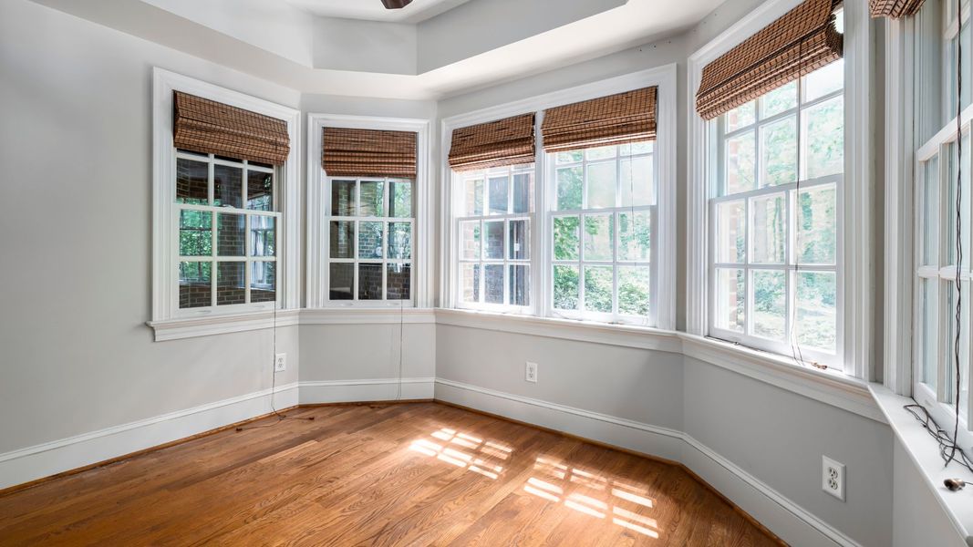 Bright room with bay windows, Roman shades, and hardwood floors