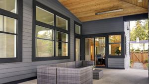 Modern home exterior with black-frame sliding glass windows and covered patio